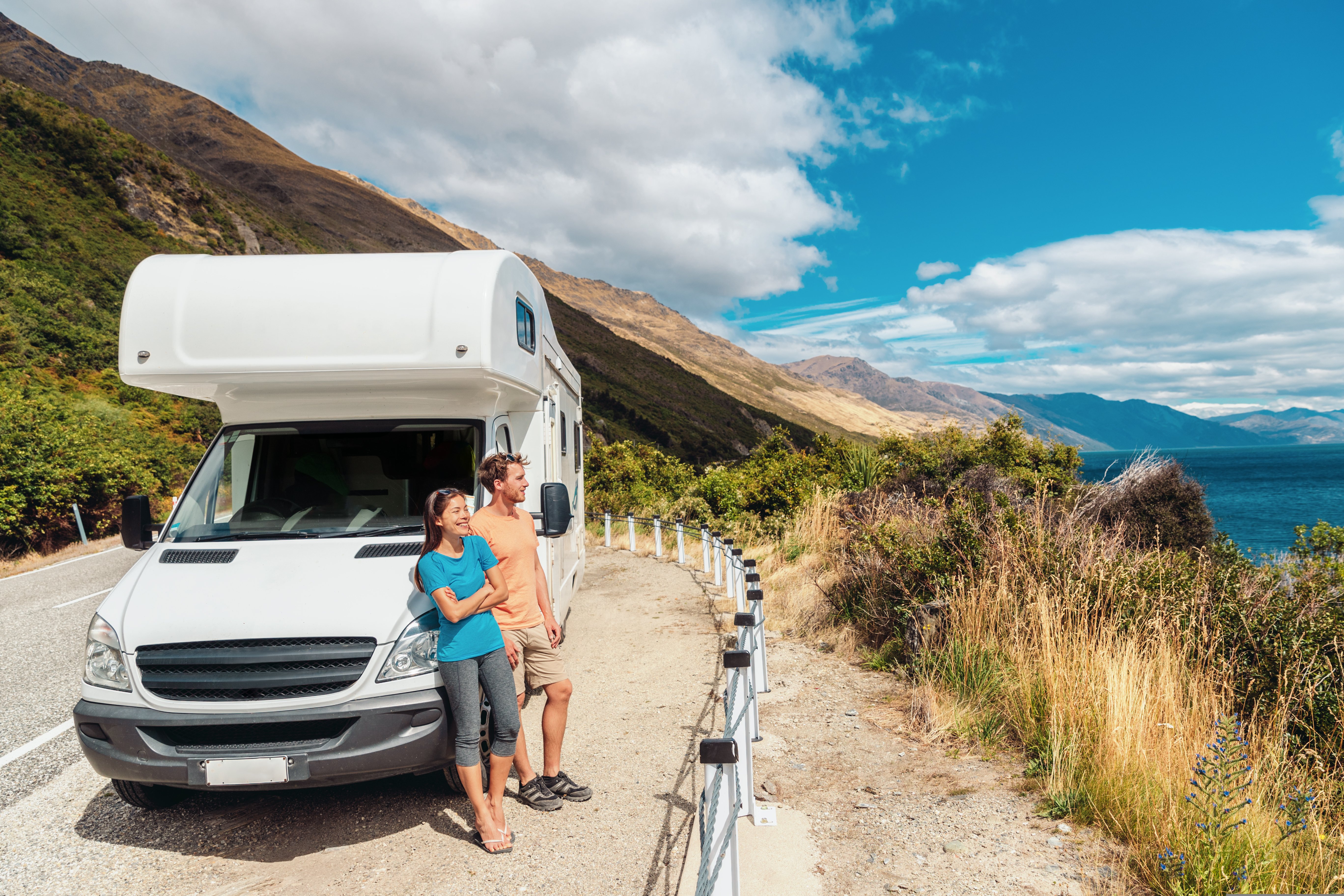 Two friends leaning against their camper van taking in the beautiful mountainous view