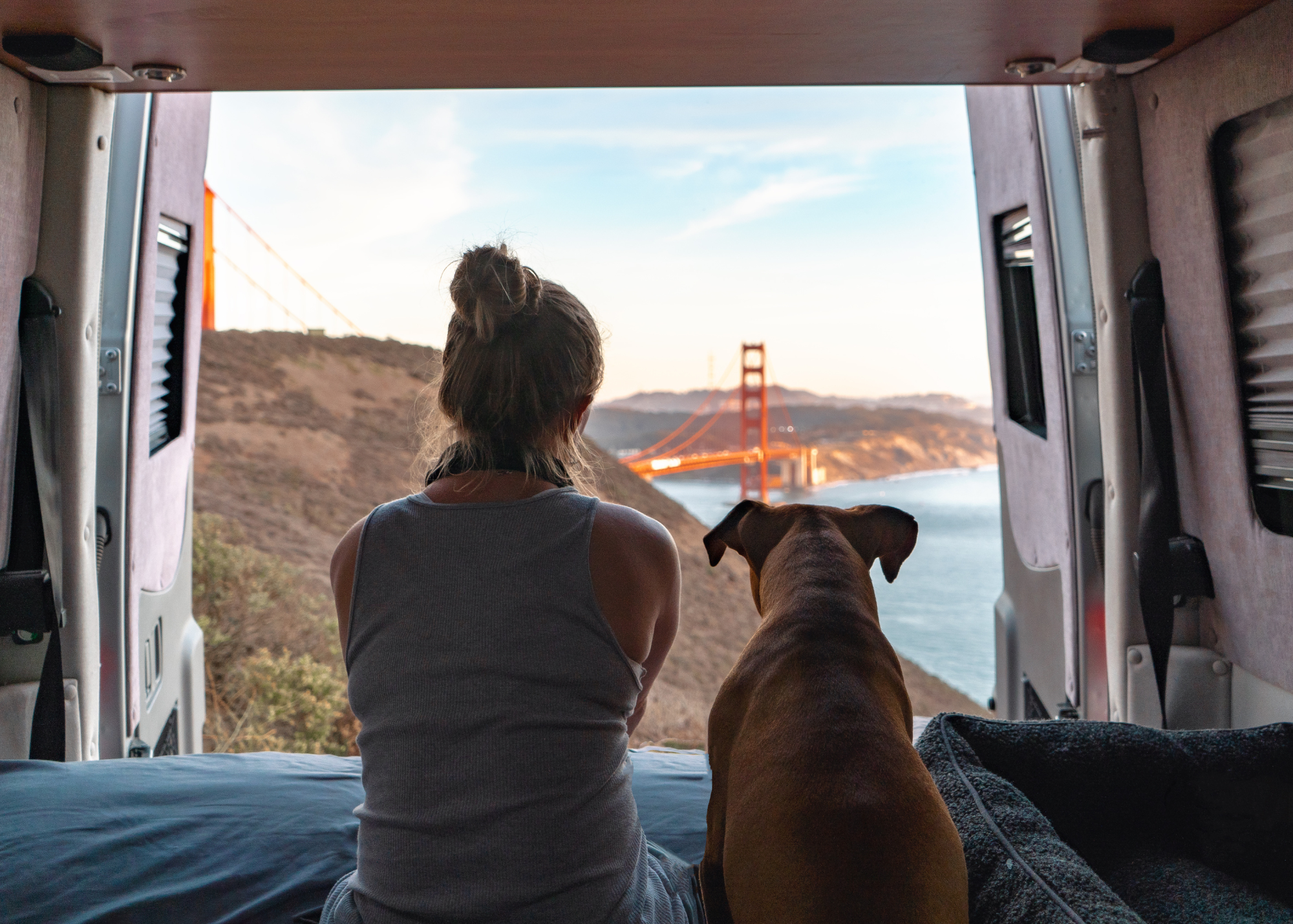 Woman and dog stare out to the view from RV van